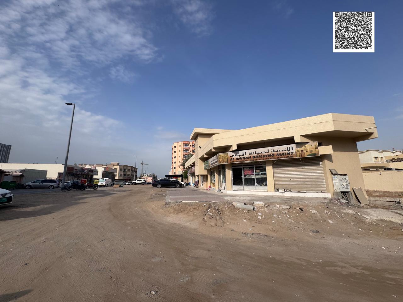 Land for sale in Ajman, Al Rawda 1. Area: 10,000 sq ft. Residential/Commercial. Part of the land has a building with 6 shops directly on Mecca Street.