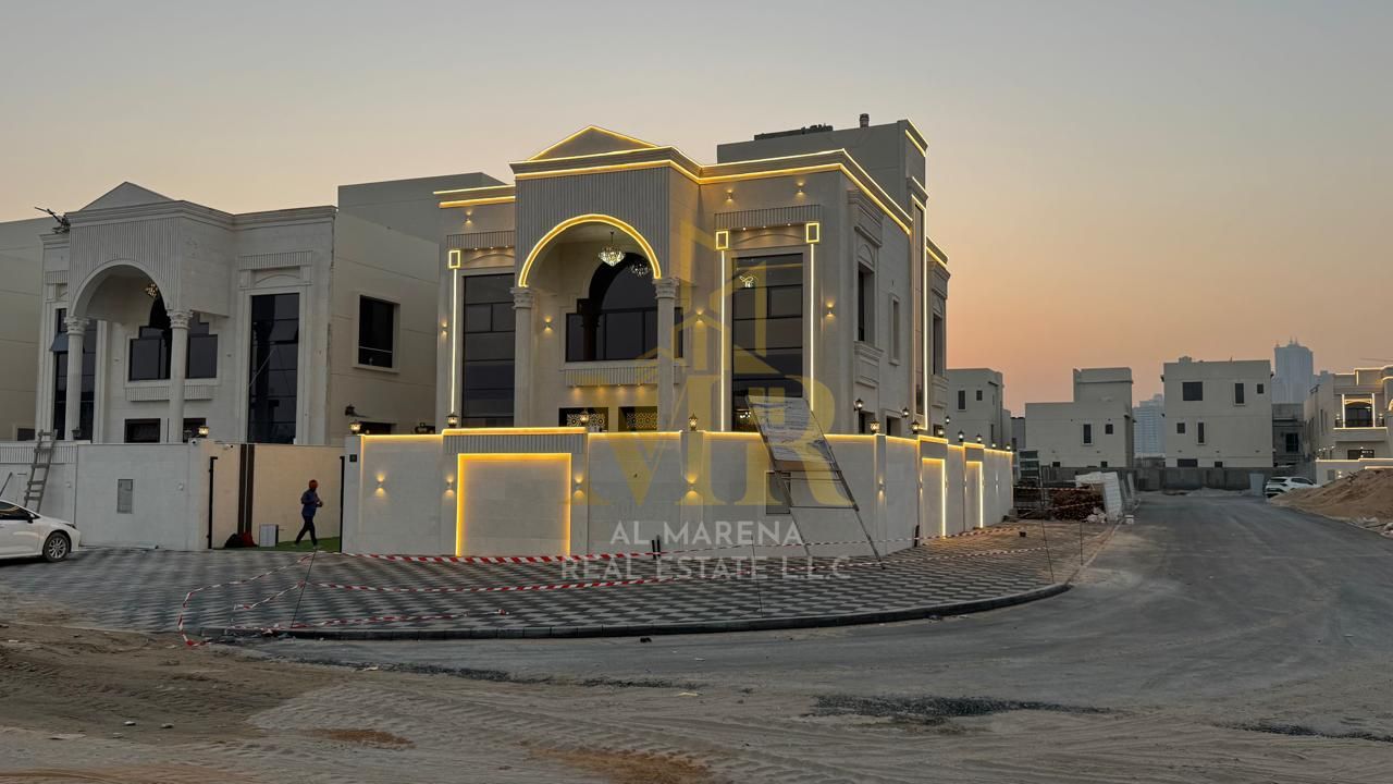 A luxurious and elegant corner villa for sale in Ajman. This two-story villa features a classic design, high-end finishes, and a rooftop terrace. The