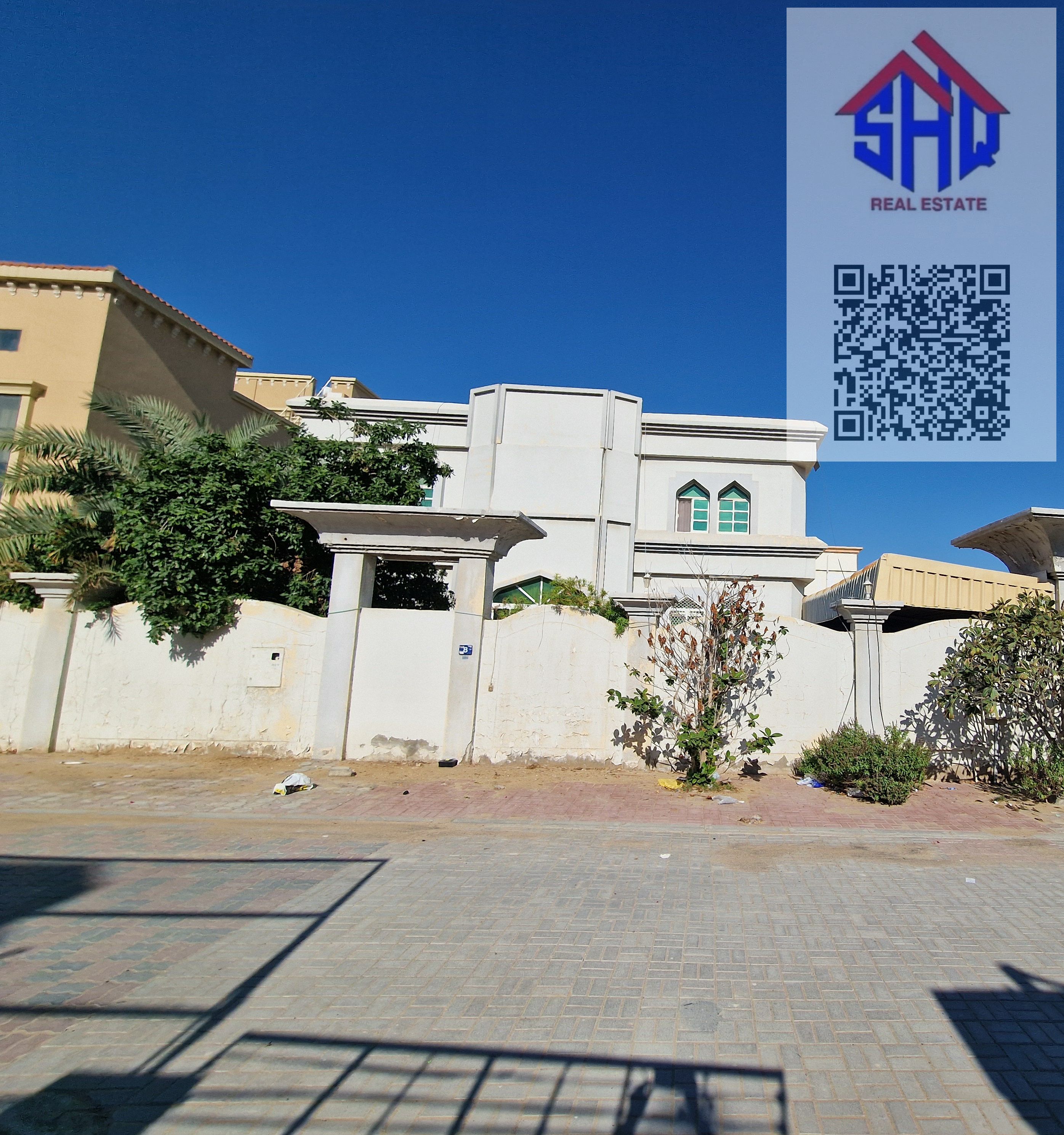 Villa for sale in Al Muwaihat area, near a mosque. Includes water, electricity, and air conditioning. 7 rooms, living room, majlis, and bedroom + storage room.