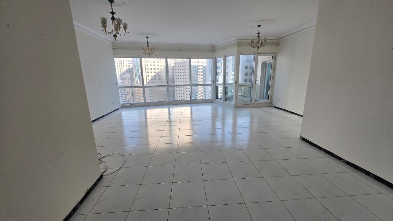 Three-bedroom apartment with living room in Al Majaz 2 Corniche, free AC, four bathrooms, balcony, open panoramic view, spacious layout, rent 72,000 A
