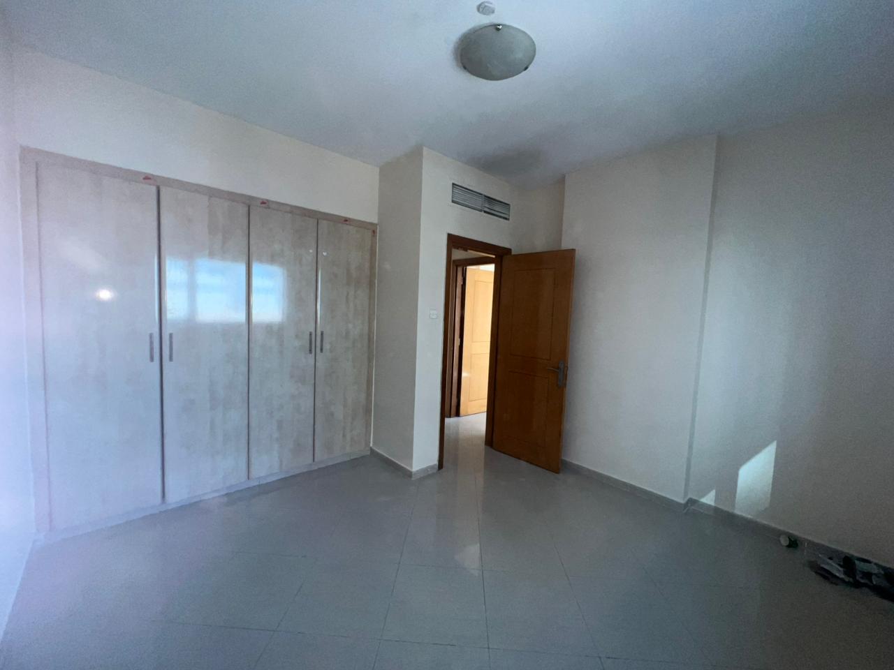 Two-bedroom apartment in Al Nahda Sharjah with open view, two bathrooms, built-in wardrobes, optional paid or sandy parking, near Sahara Center.