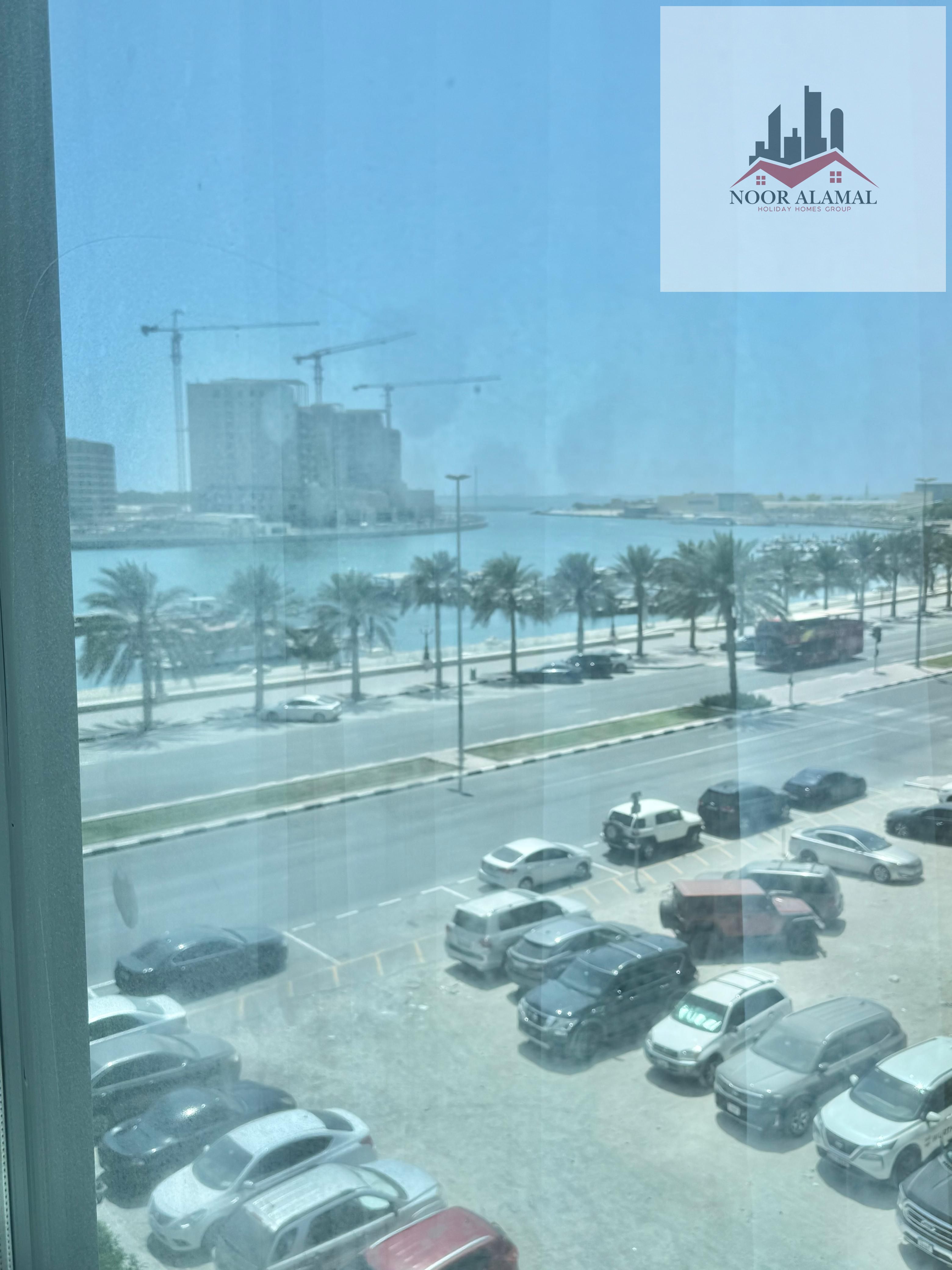 Sharjah Al Khan Furnished studio with second hotel furniture, occupant, large area, room, separate kitchen, bathroom, and large window with sea view.